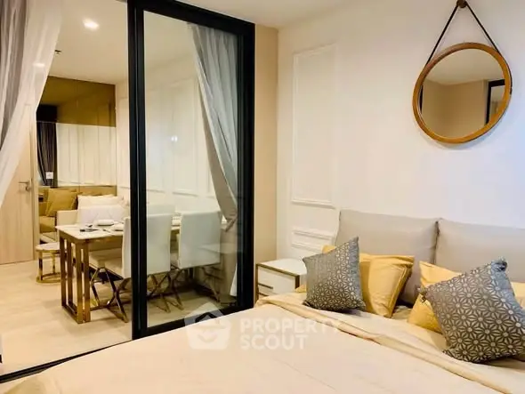 Modern bedroom with elegant decor and view into stylish dining area through glass partition.