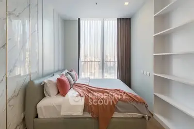 Modern bedroom with large window and stylish decor in a high-rise apartment.