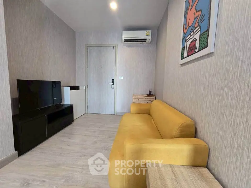 Modern living room with yellow sofa and wall art, featuring sleek TV unit and air conditioning.
