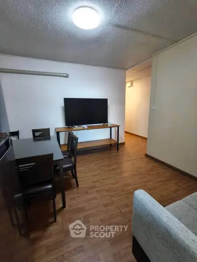 Cozy living room with wooden flooring, modern furniture, and a flat-screen TV, perfect for relaxation.
