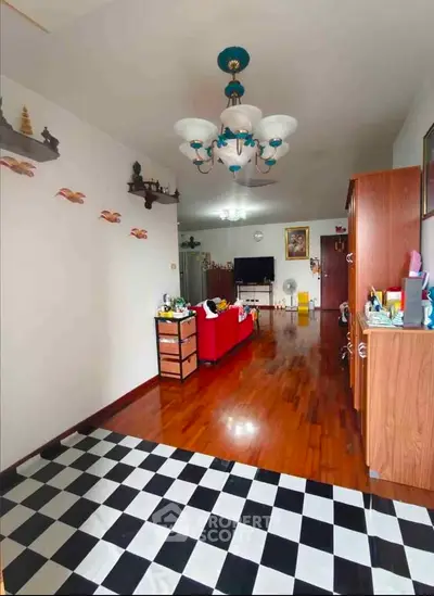 Spacious living room with unique checkered flooring and elegant chandelier, perfect for family gatherings.