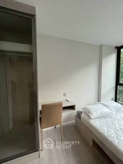 Modern bedroom with minimalist design, featuring a cozy bed and a sleek workspace.