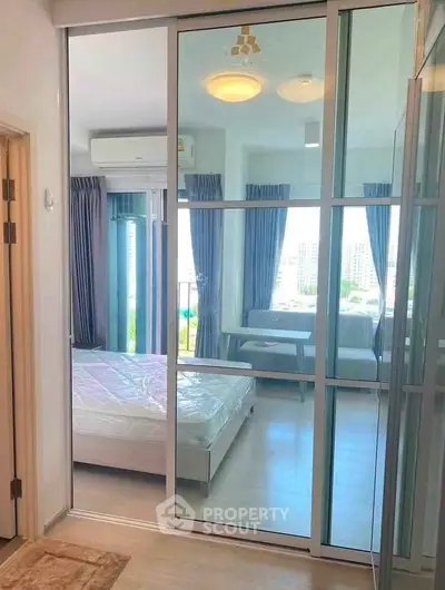 Modern bedroom with glass sliding doors and city view, featuring sleek design and ample natural light.
