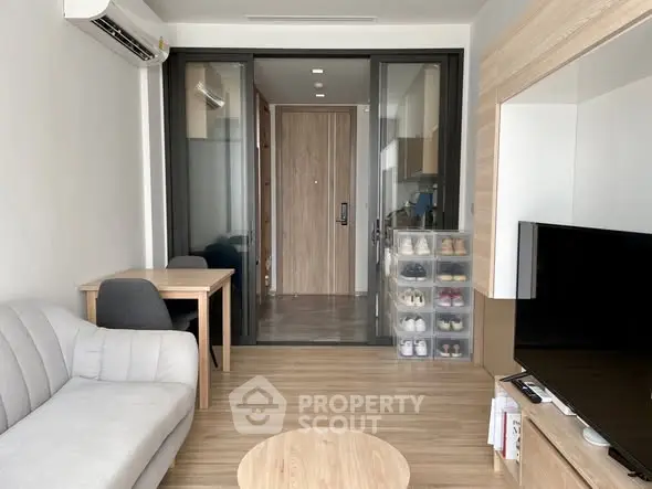 Modern living room with sleek furniture and wooden flooring, featuring a cozy sofa and a stylish TV setup.