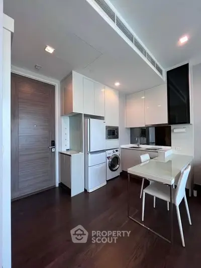 Modern kitchen with sleek white cabinets, integrated appliances, and dark wood flooring.