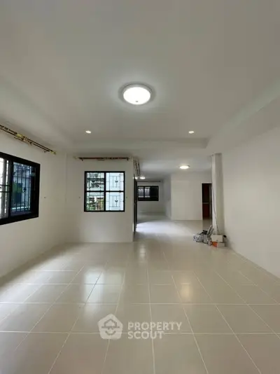 Spacious open-plan living area with tiled flooring and large windows for natural light.