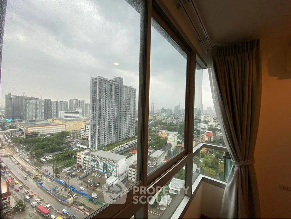 Stunning cityscape view from high-rise apartment window on a cloudy day.