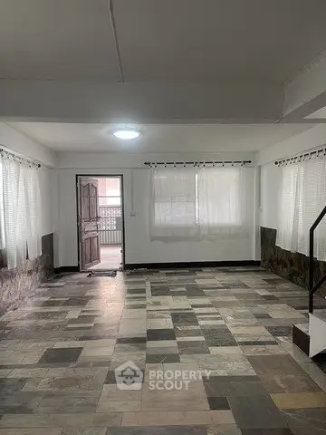 Spacious living room with tiled flooring and ample natural light, perfect for family gatherings.