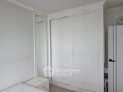 Charming bedroom with white wardrobe and mirror, perfect for cozy living.
