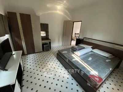 Spacious bedroom with modern furniture and stylish flooring in a well-lit apartment.