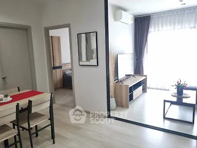 Modern living room with sleek furniture and natural light, featuring a stylish dining area and cozy bedroom view.