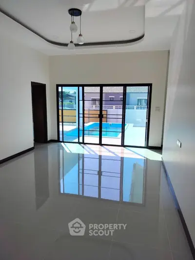Spacious living room with large windows and pool view, perfect for modern living.