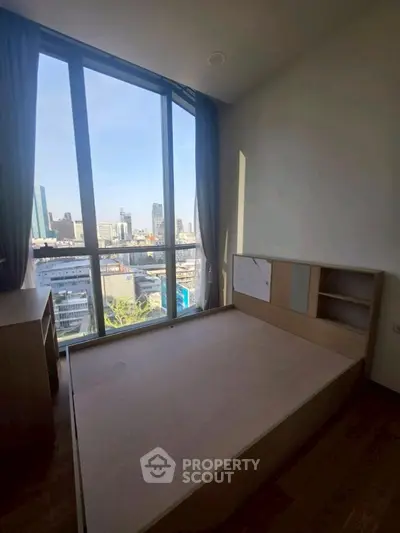 Modern bedroom with large window offering stunning city view in high-rise apartment.