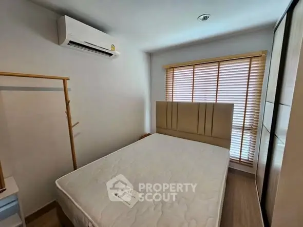 Cozy bedroom with air conditioning and natural light from window blinds.