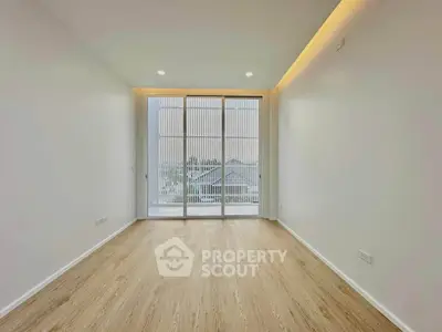 Spacious empty room with large windows and wooden flooring, perfect for customization.