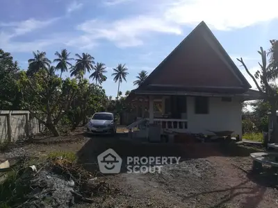 Charming tropical house with A-frame roof and lush garden setting.