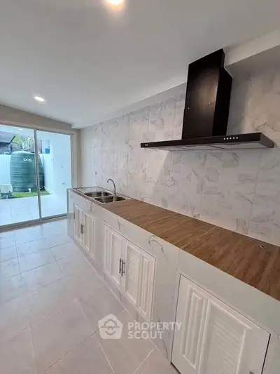 Modern kitchen with sleek cabinetry and stainless steel range hood, featuring a view of the outdoor area.