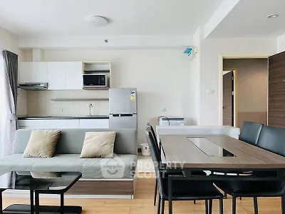 Modern open-plan living room with sleek kitchen and dining area, featuring contemporary furniture and appliances.