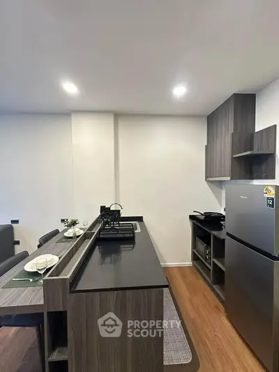 Modern kitchen with sleek design, featuring a gas stove and stainless steel fridge, perfect for culinary enthusiasts.