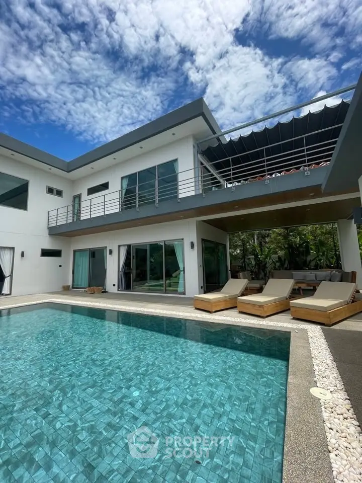 Luxurious modern villa with private pool and spacious balcony under a clear blue sky.