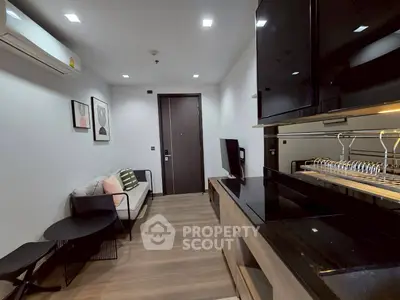 Modern living room with sleek kitchen, stylish decor, and cozy seating area, perfect for urban living.