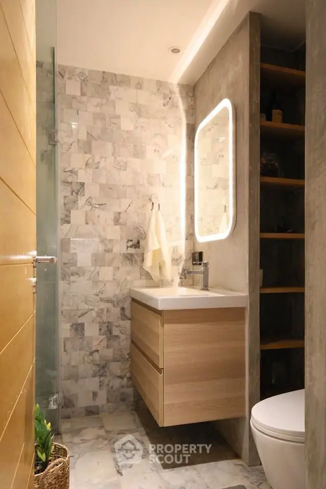 Modern bathroom with marble tiles and illuminated mirror