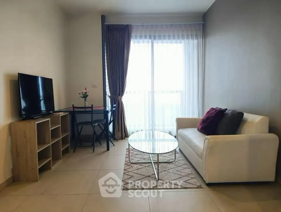 Cozy living room with modern decor, featuring a white sofa, glass coffee table, and flat-screen TV.