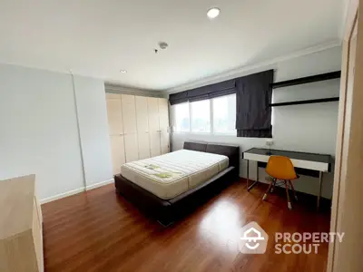 Spacious bedroom with polished wooden flooring, large bed, and ample natural light from window, perfect for restful living.