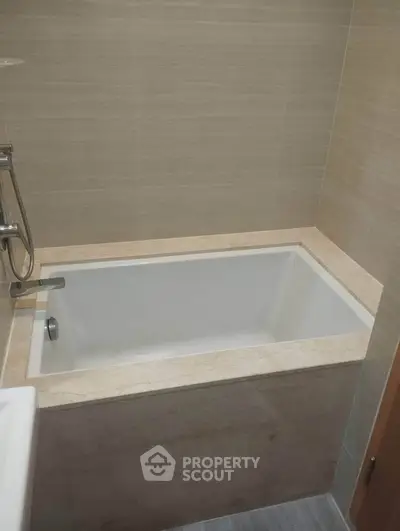 Modern bathroom with sleek built-in bathtub and neutral tile design.