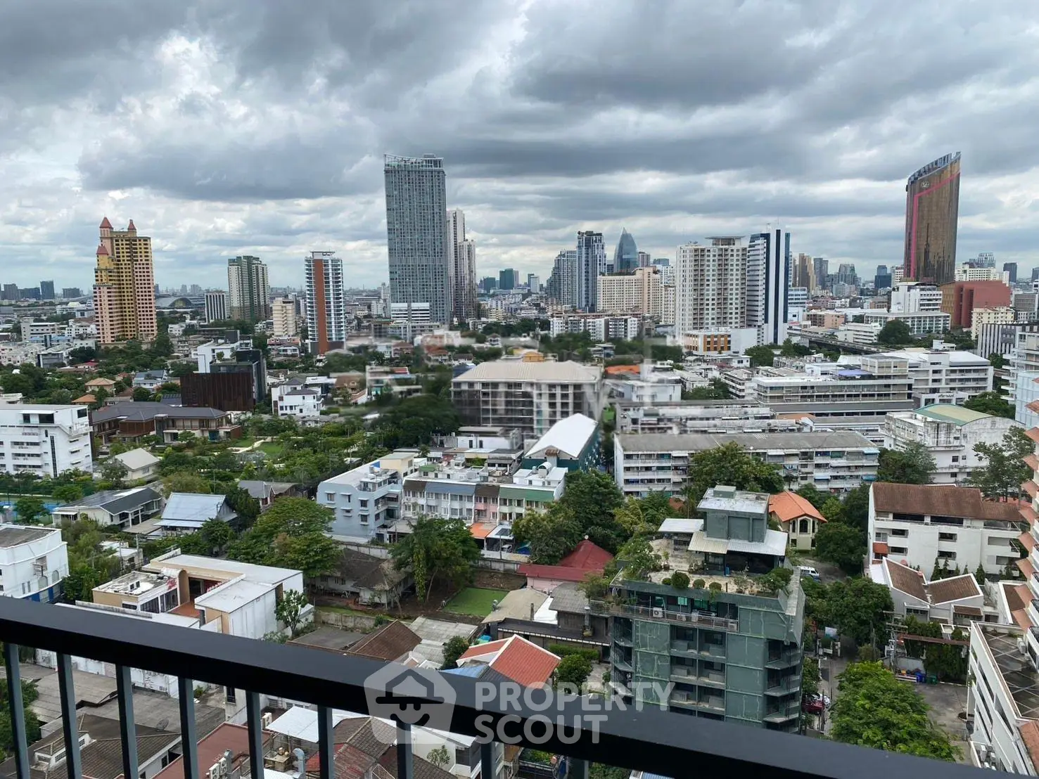 Stunning cityscape view from a high-rise balcony overlooking urban skyline and lush greenery.