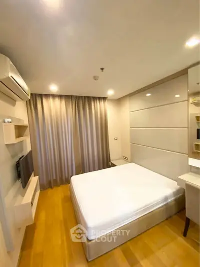 Cozy bedroom with wooden flooring and modern furnishings, featuring a comfortable bed and elegant lighting.