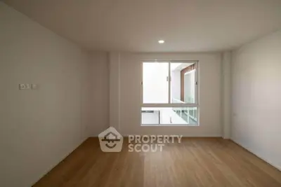 Spacious empty room with wooden flooring and large window, perfect for customization.