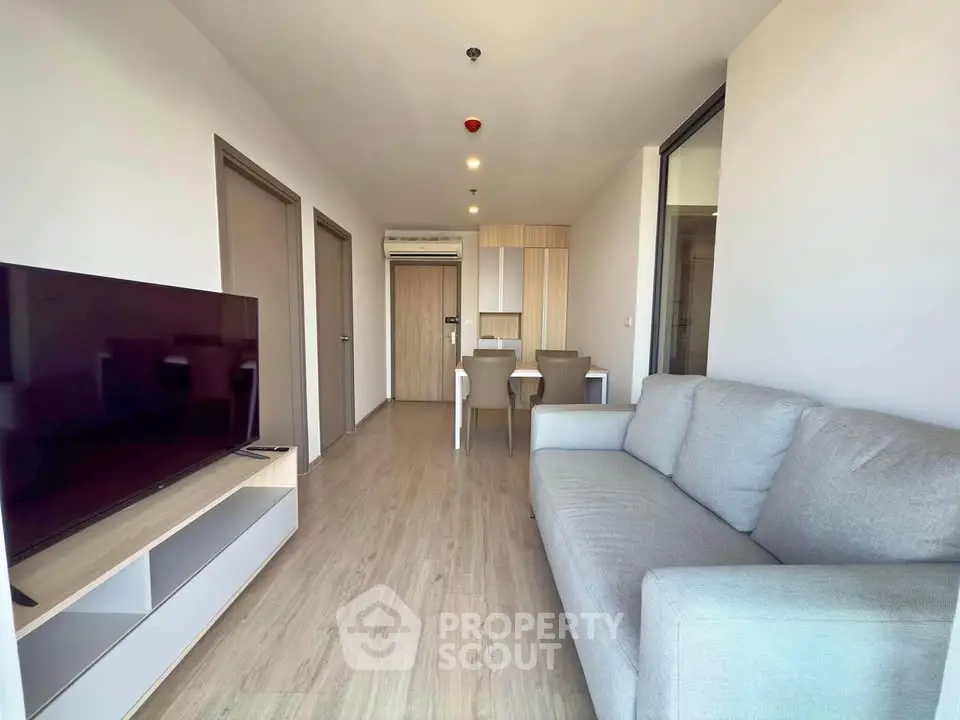 Modern living room with sleek furniture and open layout, featuring a large TV and comfortable sofa.