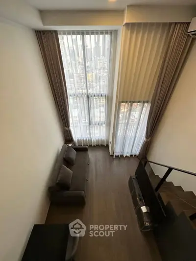 Spacious living room with high ceilings and large windows offering a stunning city view.