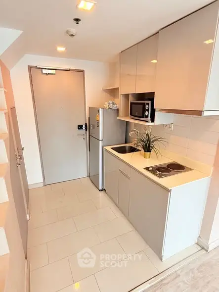 Modern compact kitchen with sleek cabinets and appliances in a cozy apartment.