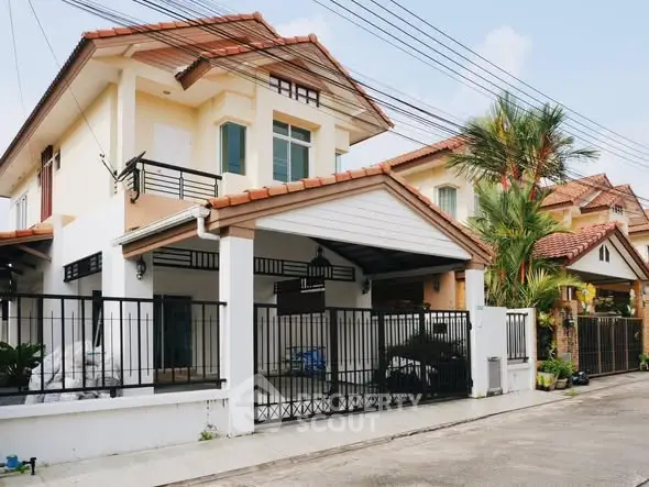 Charming two-story house with a gated driveway and tiled roof in a suburban neighborhood.