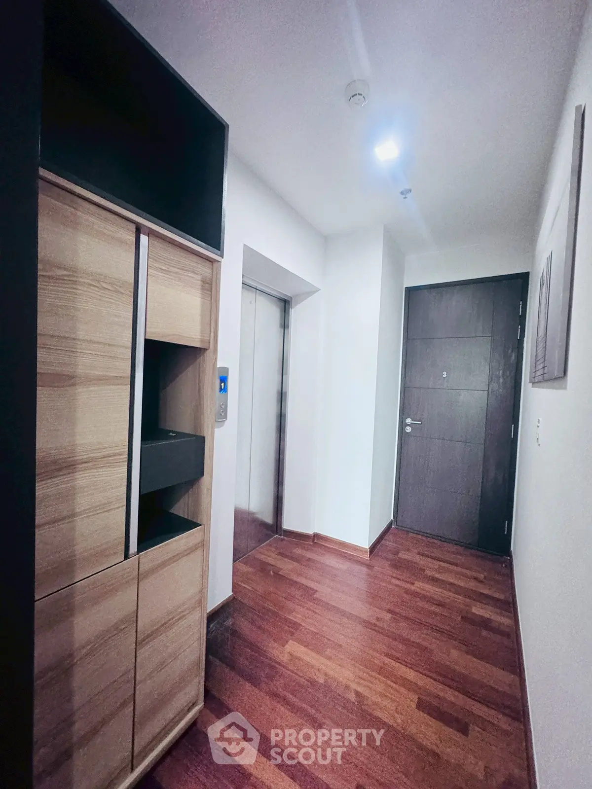 Modern apartment entrance with wooden flooring and elevator access.