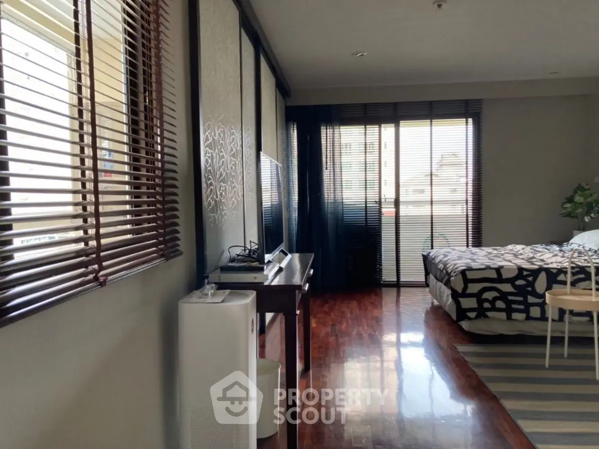 Spacious bedroom with modern decor and large windows for natural light.