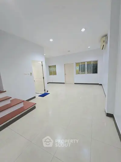 Spacious interior with tiled flooring and bright lighting, ideal for versatile living space.