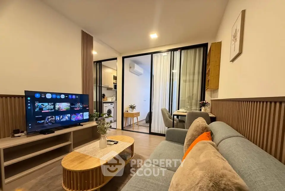 Modern living room with cozy sofa, TV, and open kitchen in stylish apartment.