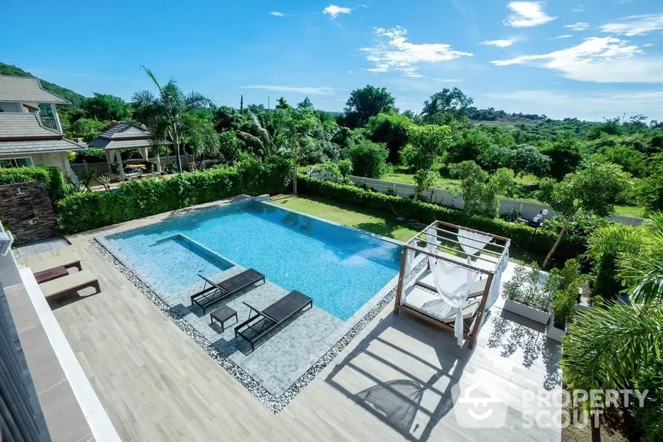 Luxurious outdoor pool with sun loungers and lush greenery in a serene setting