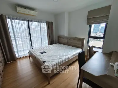 Spacious bedroom with large windows and modern furnishings in a high-rise apartment.