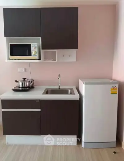 Modern compact kitchen with microwave and fridge in stylish apartment