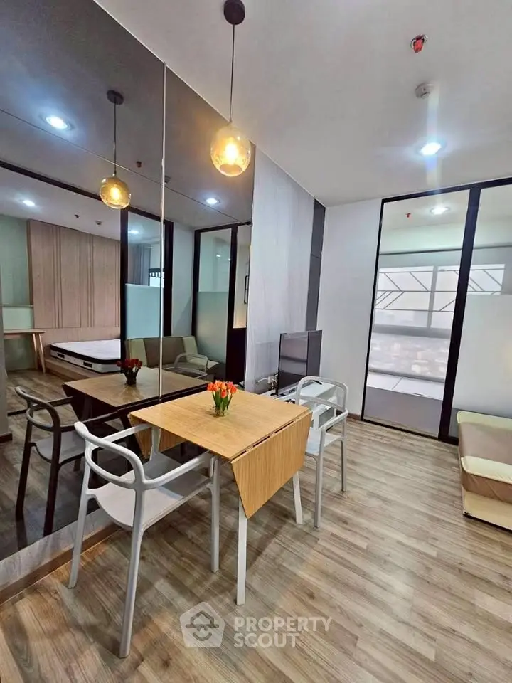 Modern living room with stylish furniture and wooden flooring, featuring a cozy dining area and ambient lighting.