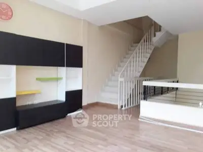 Spacious modern living room with sleek staircase and stylish shelving unit.