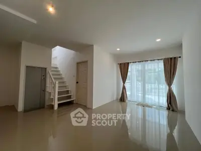 Spacious modern living room with large windows and staircase, ideal for family gatherings.