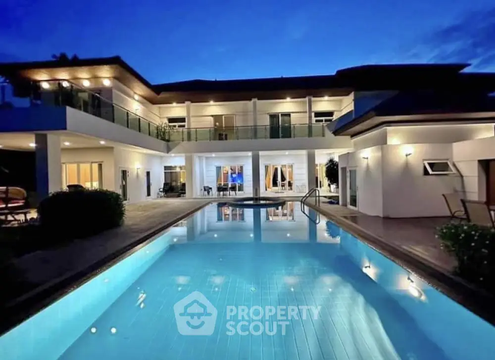 Luxurious modern villa with illuminated pool and spacious balconies at dusk