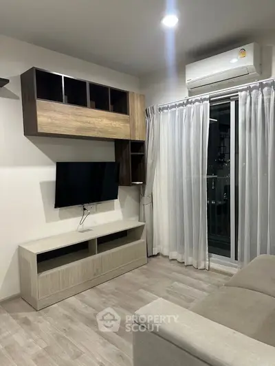 Modern living room with sleek furniture and air conditioning, featuring a wall-mounted TV and large window.