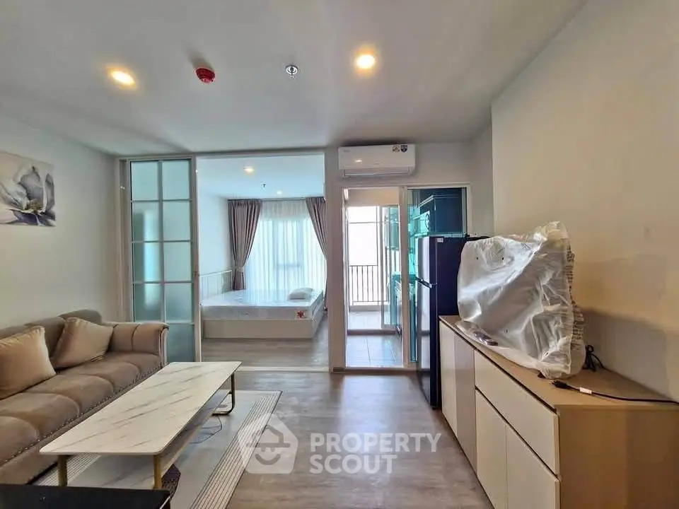 Modern open-plan living room with cozy sofa and adjacent bedroom in stylish apartment.