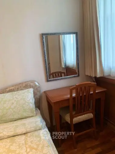 Cozy and inviting bedroom with classic wooden furniture, a comfortable single bed, and a large mirror reflecting natural light from the window.